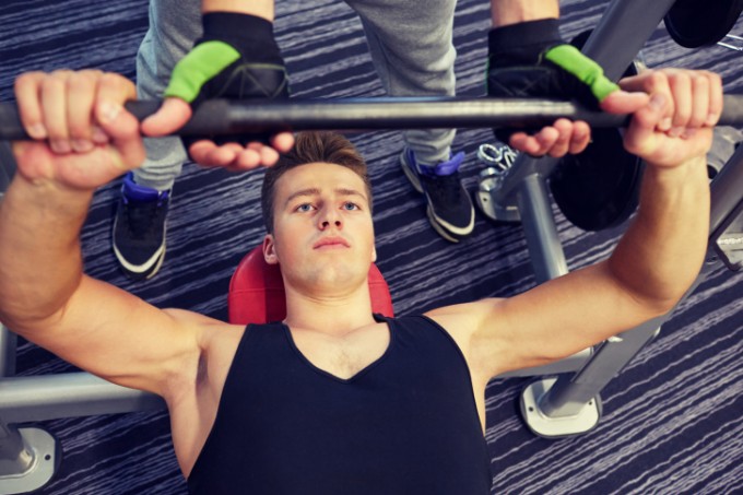 men doing barbell bench press in gym